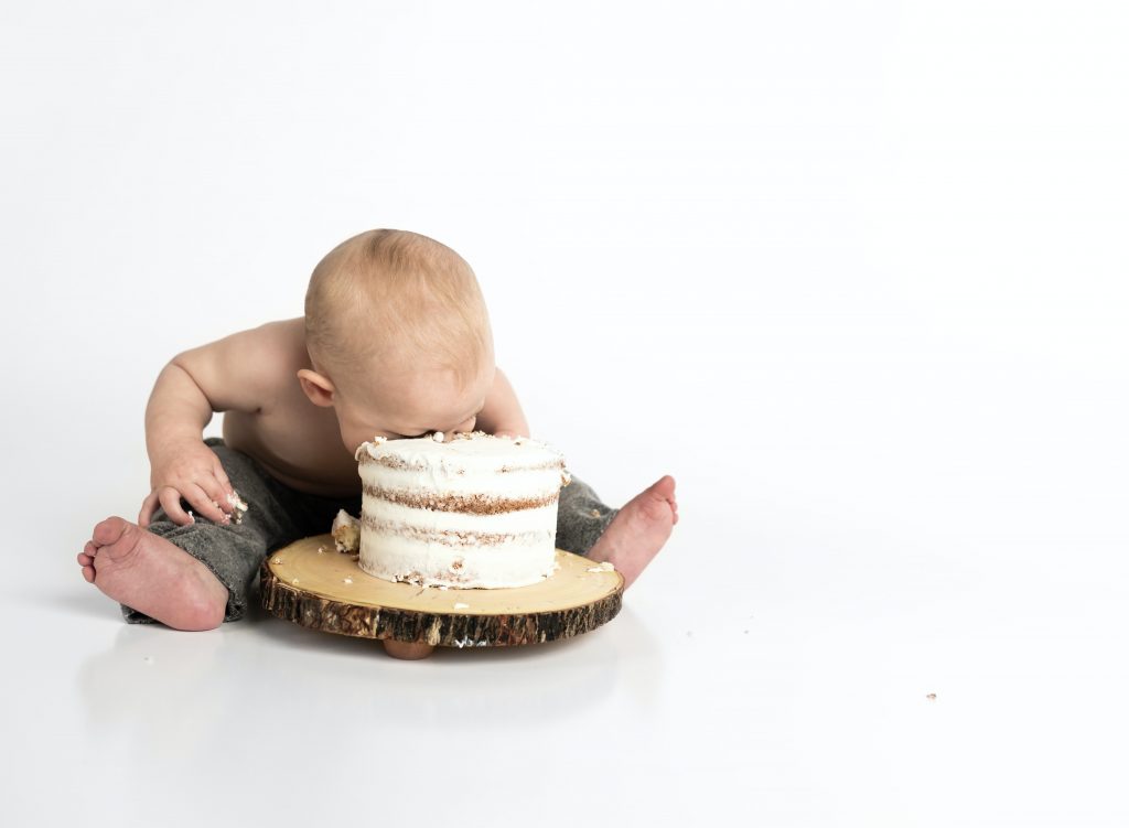baby boy puts his face in a cake